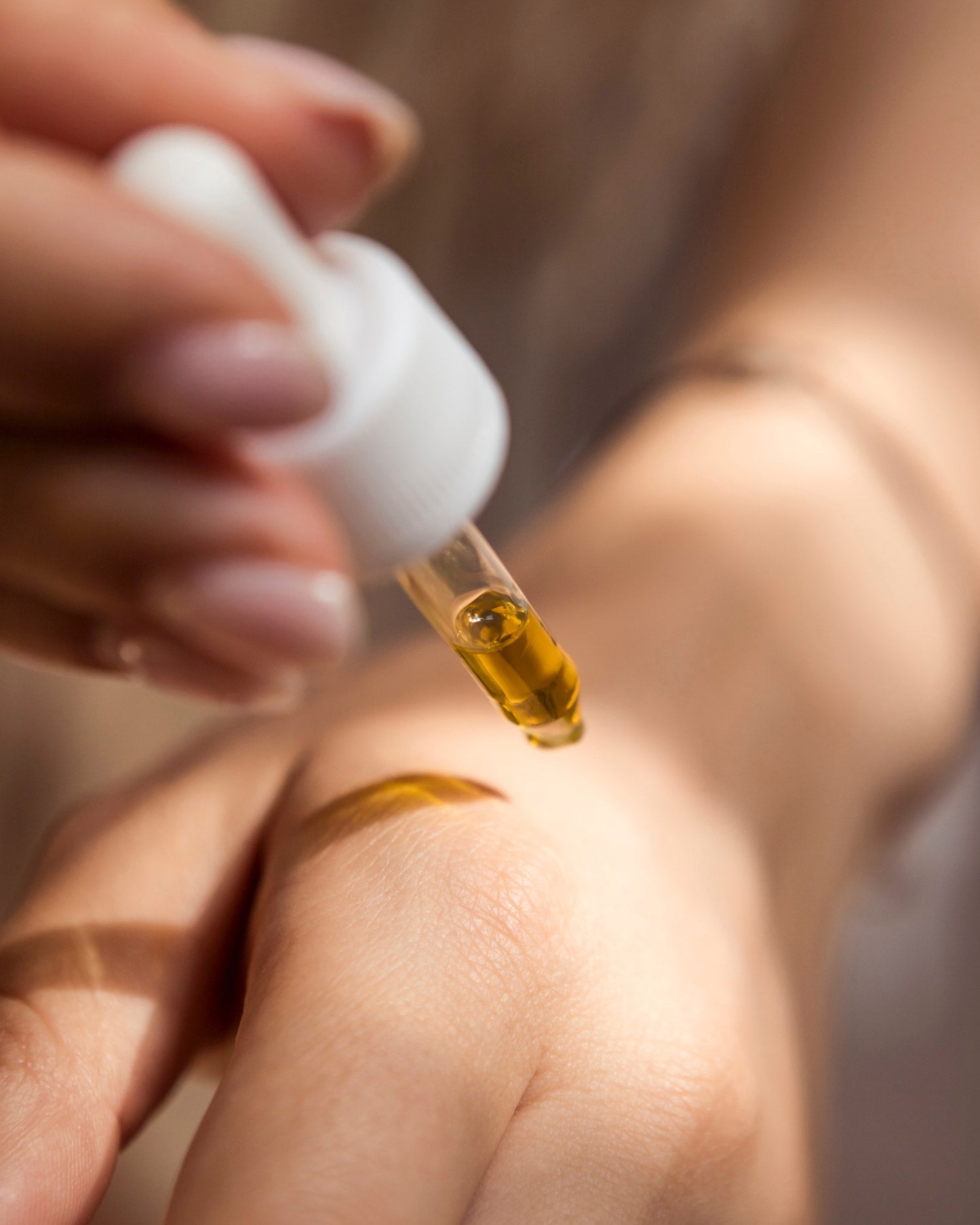 A Sonture handmade body is being dropped onto a hand from a white dropper top bottle.