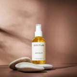 Sonture’s Amalfi Nourishing handcrafted body oil is travel inspired and features ethical ingredients. Here the luxurious self care product sits in glass packaging with a cream label in a shadowy beige background.