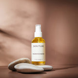 Sonture’s Marrakesh Nourishing handcrafted body oil is travel inspired and features ethical ingredients. Here the luxurious self care product sits in glass packaging with a cream label in a shadowy beige background.