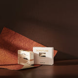 Sonture’s Jaipur handcrafted natural soap bar is inspired by travel and features nourishing natural ingredients. Here the luxurious self care product sits in a cream coloured box with a diet in a deep chocolate brown background with rust red paper. 